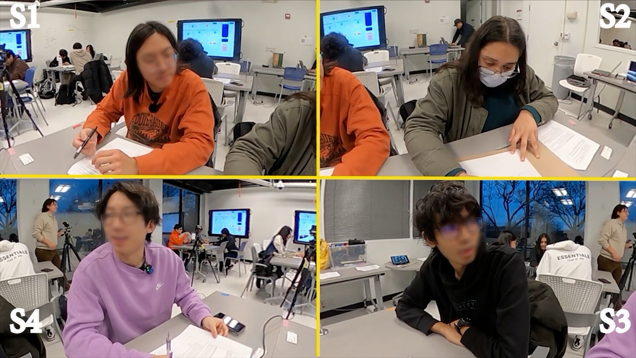 Front-facing classroom frame with faces obscured, showing a student oriented toward another student.
